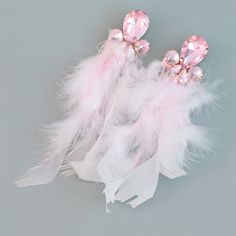 two pink and white feathers with crystal brooches on them, one is laying down