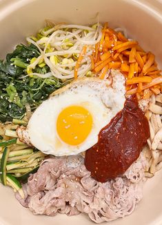 a bowl filled with meat, vegetables and an egg