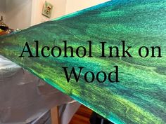 there is a sign that says alcohol ink on wood in front of a bed with white sheets