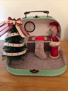 an open suitcase with a christmas tree and decorations in it sitting on a wooden table