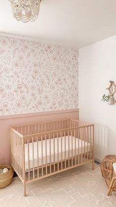 a baby's crib in the corner of a room with pink wallpaper