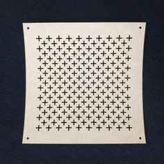 a black and white cross stitched wall hanging on a blue background with an embroidered square in the middle