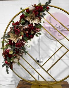 a circular sculpture with flowers and greenery on it in front of a white brick wall