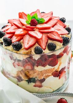 a trifle with strawberries and cream in a glass dish on a white table