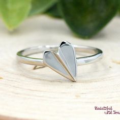 a heart shaped ring sitting on top of a piece of wood next to a plant