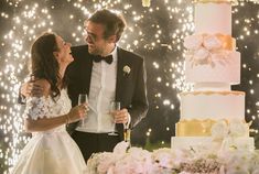 a man and woman standing next to each other in front of a cake