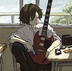 a person sitting at a table with a guitar in front of him and a radio on the desk behind them