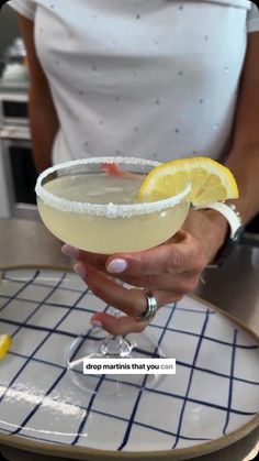 a close up of a person holding a drink on a plate with lemon wedges