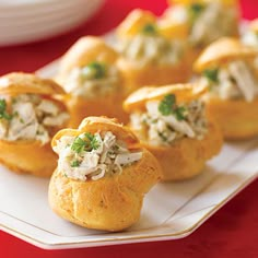 small appetizers on a white plate sitting on a red table