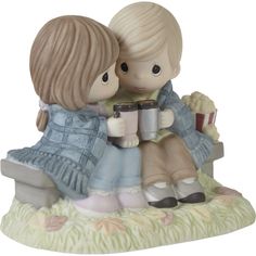 a figurine of two children sitting next to each other on a bench holding books