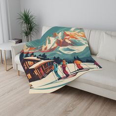 a couch with a blanket on top of it that has skiers skiing down the mountain