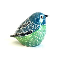 a small blue and green bird sitting on top of a white table next to a wall