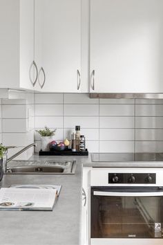 a white kitchen with stainless steel appliances and counter tops, along with an open cookbook