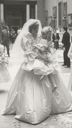 an old black and white photo of two women in wedding dresses, one holding a baby