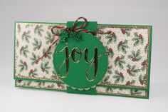 a christmas card with the word joy on it and a green ornament hanging from the front