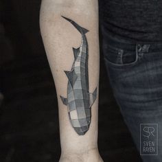 a black and white photo of a shark tattoo on the left inner arm, with checkered pattern