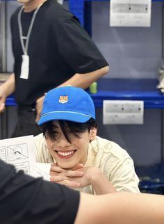 a young man wearing a blue hat and holding a piece of paper in his hand