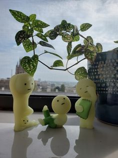 three little figurines sitting next to each other on a table in front of a window