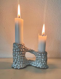 two white candles sitting on top of a table