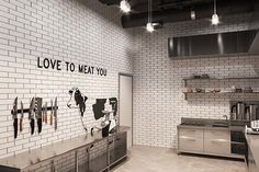 an industrial kitchen with white brick walls and stainless steel appliances on the wall, along with black lettering that reads love to meat you