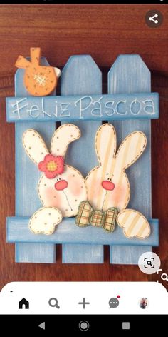 a wooden sign with two rabbits and a bird on it's head that says feliz pascoa