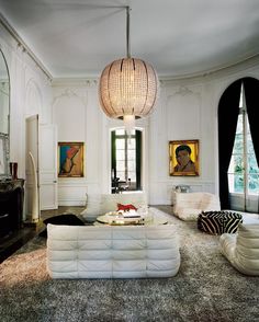 a living room filled with furniture and a large painting on the wall above it's fireplace