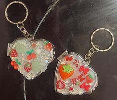 two heart shaped keychains with fruit and vegetables on them sitting next to each other