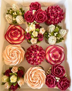 a box filled with cupcakes covered in pink and red frosting flowers on top of each other