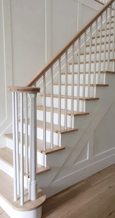 a white staircase with wooden handrails in a house