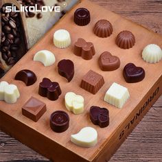 a wooden box filled with lots of different types of chocolates on top of a table