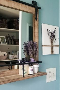 lavenders are arranged on the shelf in front of a mirror and light switch box