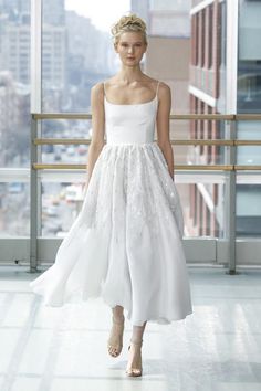 a woman walking down a runway in a white dress