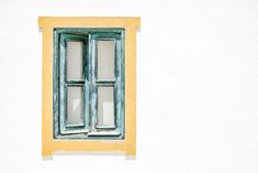 an old window is painted yellow and has green trim on the windowsill, with white walls