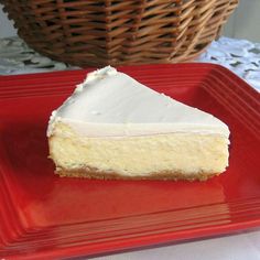 a piece of cheesecake on a red plate with a basket in the back ground