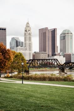 the city skyline is shown with tall buildings and a bridge in the foreground, on a cloudy day