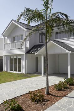 a palm tree is in front of a white two - story house with balconies