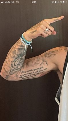 a man with tattoos on his arm pointing at something