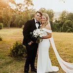 a bride and groom pose for a photo in front of the sun at their wedding