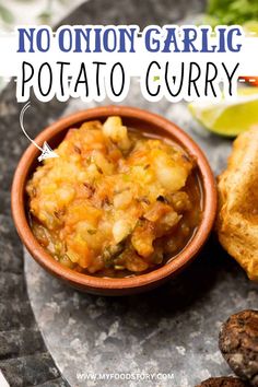 a bowl filled with potato curry on top of a table next to bread and vegetables