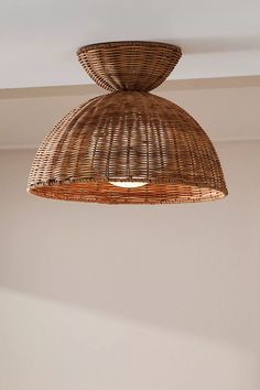 a wicker light fixture hanging from the ceiling in a room with beige walls and flooring