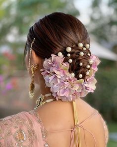 a woman with flowers in her hair is wearing a pink dress and gold jewelry on her neck