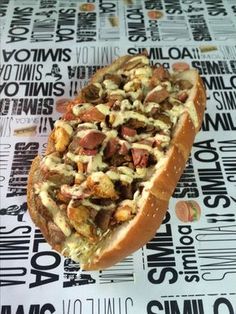 a hot dog covered in toppings sitting on top of a table