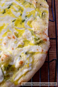 a pizza with cheese and broccoli on it sitting on a wire cooling rack