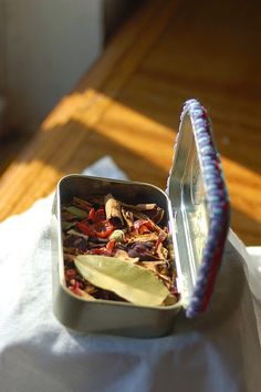 an open tin with some food inside of it on a white cloth next to a wooden table