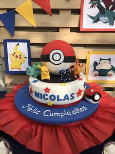 a pokemon themed birthday cake with figurines and pictures on the wall behind it