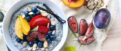 a bowl of oatmeal topped with fruit and nuts next to sliced peaches