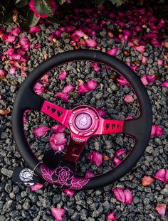 a pink steering wheel sitting on top of a pile of flowers