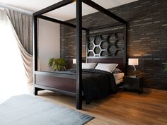 a bedroom with a four poster bed and brick wall behind the bed, along with a rug on the floor