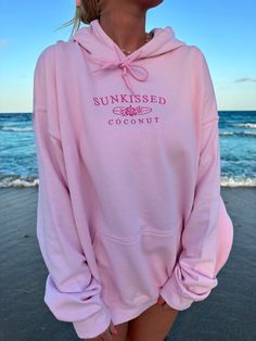 a woman wearing a pink hoodie on the beach