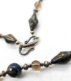 Apache pyrite, lapis lazuli and smoky quartz beaded sterling silver artisan necklace. The beads on this unique necklace are one of a kind. Each gemstone bead is unique in the pyrite inclusions that are found through out the stones. The Apache pyrite elongated bicone beads are full of amazing color and heavy. The lapis lazuli is mottled with a large amount of shining gold highlights through the blue lapis. There are sterling silver and smoky quartz beaded spacers between. Stamped 925 on the hook Artisan Necklace, Gold Highlights, Blue Lapis, Unique Necklace, Unique Necklaces, Smoky Quartz, Lapis Lazuli, Gemstone Beads, Highlights